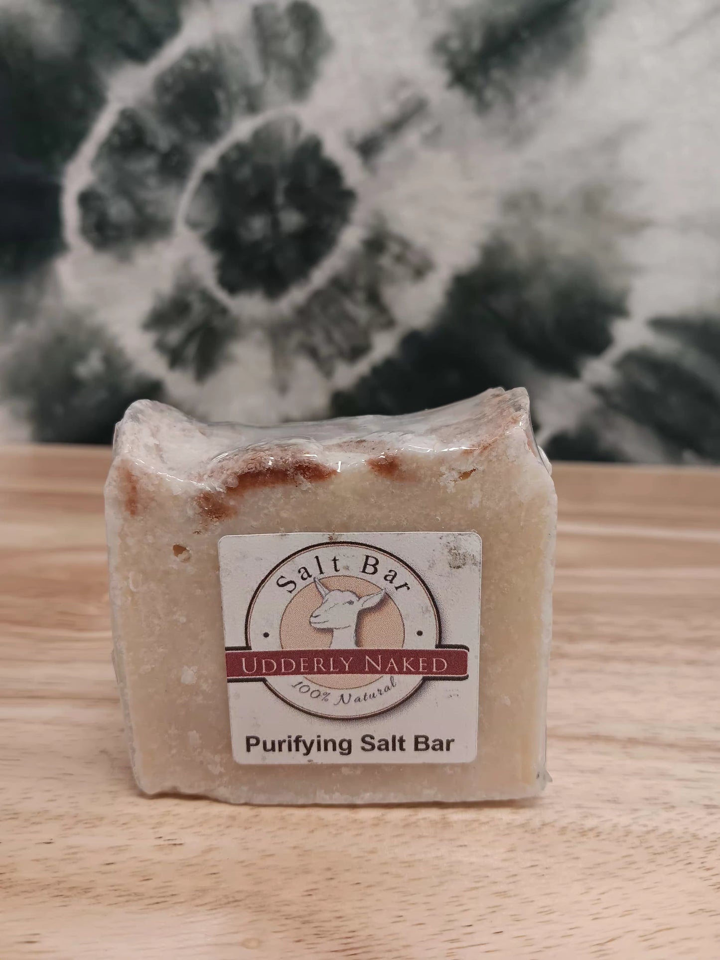 Purifying Salt Bar soap with a label on a wooden surface and floral background