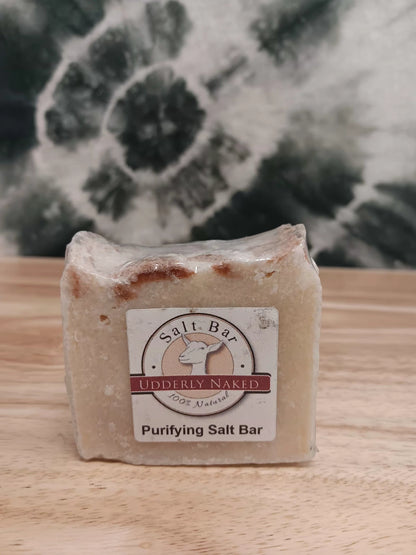 Purifying Salt Bar soap with a label on a wooden surface and floral background