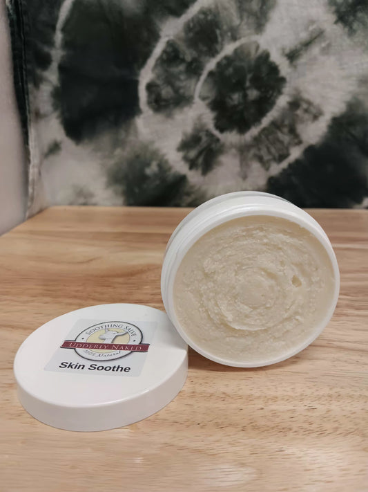 Open jar of 'Skin Soothe' cream on a wooden surface with a black and white floral pattern in the background.
